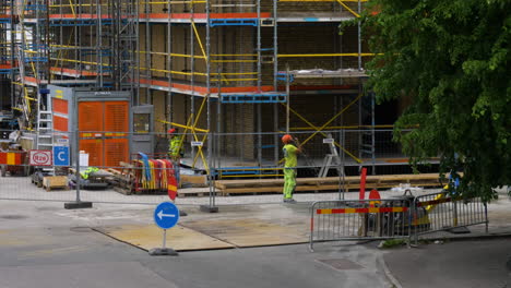 Construction-Worker-Walks-And-Talks-On-Two-way-Radio-At-The-Development-Site-In-Gothenburg,-Sweden