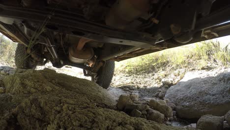 Close-Up,-Undepart-on-Offroad-Cruiser-Vehicle-Moving-on-Rocky-Ground-in-Outback-Low-Angle