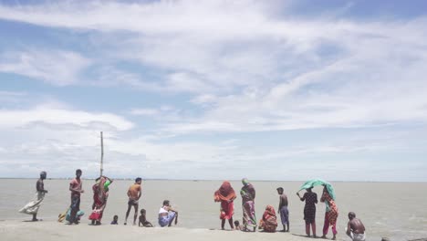 People-standing-at-the-riverside-after-the-flood-has-washed-away-their-homes