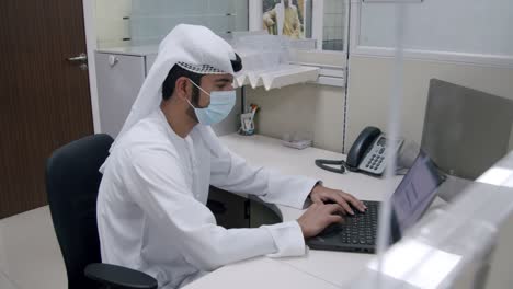 Ein-Arabischer-Mann,-Der-Im-Büro-An-Seinem-Laptop-Arbeitet---Totale