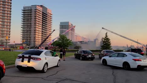 Espectadores-Curiosos-Siguen-El-Trabajo-De-Los-Equipos-De-Bomberos-Que-Luchan-Contra-Un-Incendio-Que-Estalló-En-El-Restaurante-Paramount-Fine-Foods-En-El-Centro-De-La-Ciudad-De-Erin-Mills-En-Mississauga,-Ontario,-Canadá.