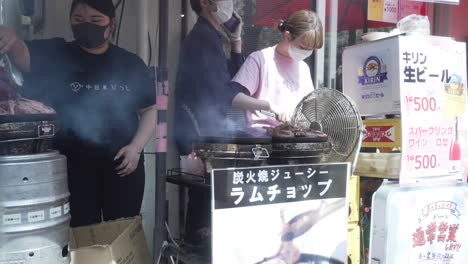 Vendedores-Japoneses-De-Comida-Callejera-Con-Máscaras-Asando-Carne-En-Tokio,-Japón---Tiro-Estático