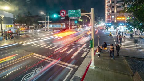 Lapso-De-Tiempo-Nocturno-Con-Vistas-A-La-Intersección-De-La-Carretera-Este-De-Zhongxiao-Con-Senderos-De-Tráfico-Y-Peatones-Que-Pasan-Por-La-Concurrida-Ciudad-Metropolitana-De-Taipei,-Taiwán