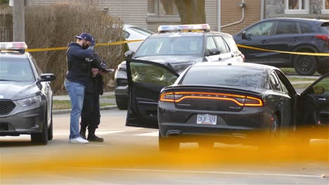 Police-investigating-a-car-shot-up-with-bullet-holes-Still-shot-with-yellow-tape-in-foreground