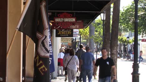 People-walk-along-the-bars,-restaurants-and-shops-on-famous-Duval-Street-in-Key-West,-Florida,-USA