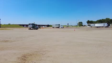 Student-learning-how-to-maneuver-a-semi-tractor-and-trailer-backwards-in-a-large-empty-lot