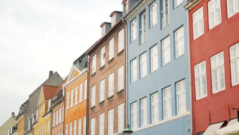 Gente-En-La-Colorida-Fachada-De-Edificios-Residenciales-En-El-Distrito-De-Nyhavn-En-Copenhague,-Dinamarca