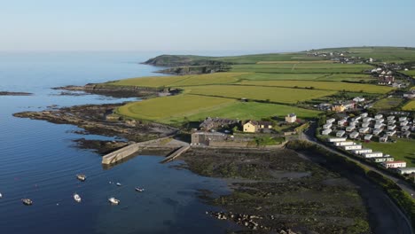 An-aerial-over-popular-green-Old-Head-peninsula-near-Kinsale,-Ireland-with-calm-ocean-and-camping-site
