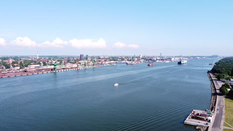 Vast-sea-entrance-of-Klaipeda-harbor-with-industrial-buildings-and-city-skyline,-aerial-view-on-sunny-day
