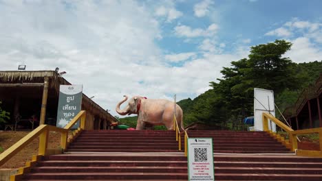 Walking-up-the-stairs-through-the-compound-of-Luang-Pu-Thuat,-a-Buddhist-Park-revealing-a-giant-elephant-sculpture,-the-symbol-of-Buddhism-in-Pak-Chong,-Thailand