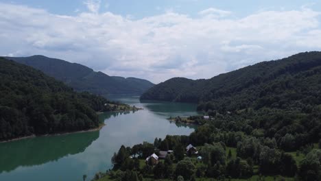 Aerial-shot-of-the-mountain-forest-meeting-the-clean-lake-of-Paltinu-of-Doftana-Valley-in-Romania