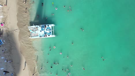 Stunning-4k-aerial-overhead-of-families-enjoying-the-sun,-surf-and-sand-as-well-as-crystal-blue-waters-at-a-luxury-vacation-resort-on-the-beach