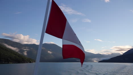 Bandera-De-Canadá-En-Ferry-Contra-El-Cielo-Azul-De-La-Mañana-Y-Las-Montañas-Costeras