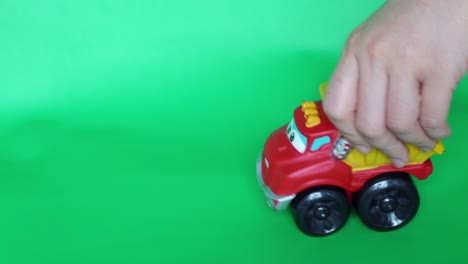 hand-of-kid-playing-toy-big-truck-chuck-with-green-background