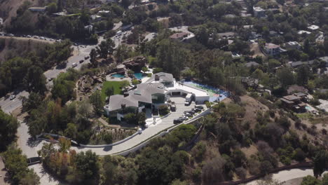 Dramatic-flyby-of-giant-mansion-with-tennis-court,-lagoon-pool,-water-slide,-putting-green-and-Coy-pond-on-Mulholland-Drive-in-Los-Angeles