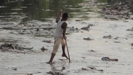 Ein-Junge,-Der-Zwischen-Abgeladenem-Müll-In-Einem-Fluss-Bei-Slums-In-Pakistan-Spazieren-Geht