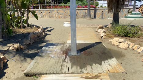 Spanish-beach-with-a-public-shower-in-city-Estepona-with-palm-trees-and-sand,-Paseo-Maritimo