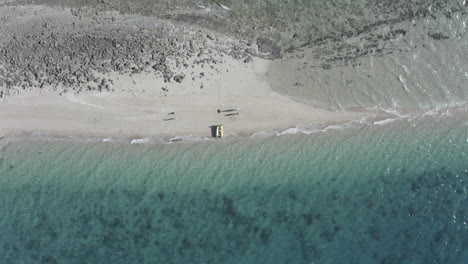 Vertikale-Antenne-Erhebt-Sich-über-Winzige-Sandinsel-Mit-Menschen-Und-Gelbem-Boot