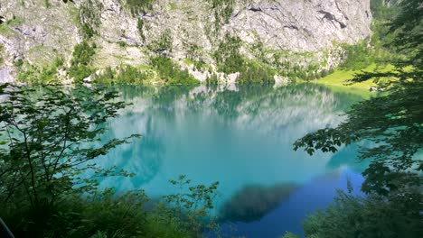 Idyllic-beautiful-nature-reserve-lake-with-vibrant-colors-in-mountain-of-Austria---Tilt-up-shot-4K---Cliff-wall-reflection-in-water-surface