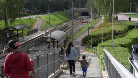 Suburban-area-district,-mother-and-child-walking-towards-tram-station,-Galileis-Gata-tram-stop,-Gärdsås-torg,-Bergsjön