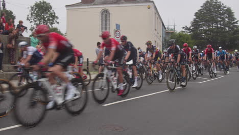 Cyclist-Team-Racers-in-Tour-of-Britain-2021-Race-Speed-by-as-Crowds-Cheer,-Cornwall,-Panning-Shot