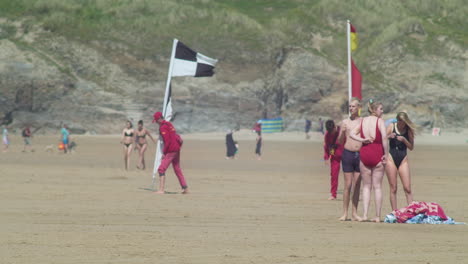 Menschen-Warten,-Während-Rettungsschwimmer-Flaggen-Der-Strandsicherheitszone-Verschieben,-Perranporth,-Cornwall,-England,-Tele