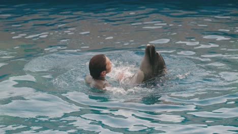 Dolphin-With-Male-Trainor-Dancing-And-Spinning-In-The-Water-For-Audience-Watching-a-Dolphin-Show-At-Umino-Mori-Aquarium-In-Sendai,-Miyagi,-Japan