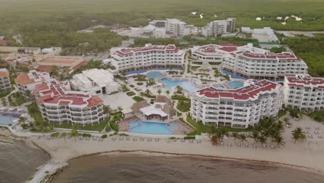 AERIAL---High-altitude-shot-of-hotel-and-swimming-pool,-Cancun,-Mexico,-circle-pan