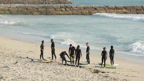 Grupo-De-Surfistas-En-Trajes-De-Neopreno-De-Pie-En-La-Playa-Del-Hospital-En-Figueira-Da-Foz,-Coimbra,-Portugal-En-Verano