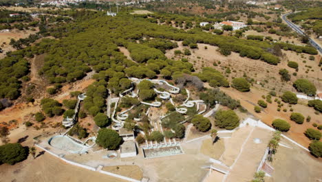 Aerial-flyover-dried-countryside-during-hot-summer-and-mysterious-old-waterpark-with-waterslides---Closed-holiday-park-in-Portugal