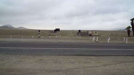 Logistics-trucks-passing-a-remote-entrance-to-a-gravel-road-Gramita,-Casma,-Ancash,-Peru