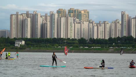Group-Of-Vacationists-On-Watersports-At-Han-River-With-Seoul-Cityscape-Backdrop-In-South-Korea