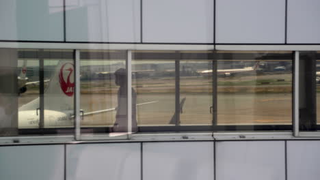 Aircraft-Pilot-Walking-Through-A-Jet-Bridge-Towards-Airplane-Parked-At-Airport-Apron