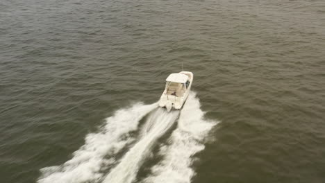 An-aerial-view-of-a-small,-white-fishing-boat-speeding-in-the-deep,-green-Atlantic-Ocean-by-Long-Island,-NY