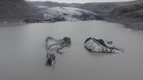 Aerial-view-over-ice-blocks-on-the-Solheimajokull-glacier-lagoon---tilt,-drone-shot