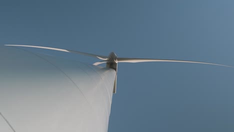 Low-angle-shot-looking-up-at-a-wind-turbine-spinning-on-a-sunny-day