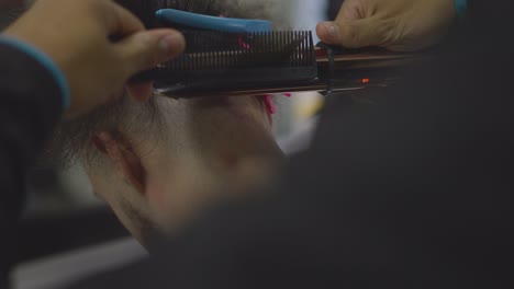 barber-combing-and-flattening-man's-hair-with-hair-dryer-in-barber-shop