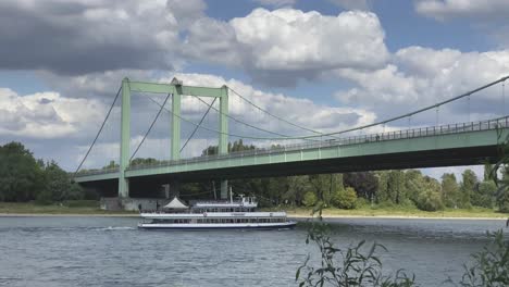 A-tourist-boat-travels-along-the-Rhine-river-and-goes-below-Muelheimer-bridge