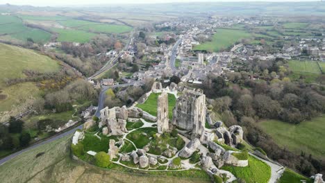 Aerial-tilt-down-forward-over-Corfe-Castle-ruins-and-village-in-background
