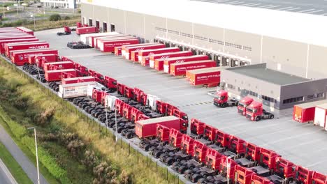 Aerial-view-rows-of-Royal-mail-delivery-trucks-parked-at-postal-depot-descending-slow