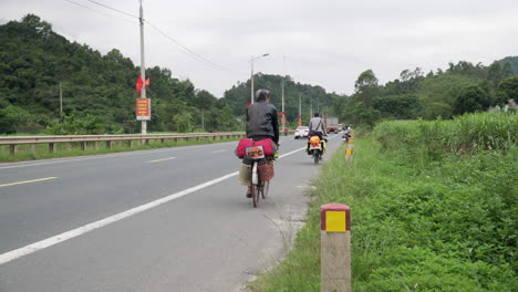 Cyclists-transiting-in-a-pavement-road-during-a-day-road-trip-through-asia