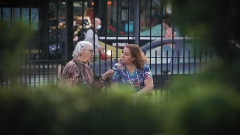 Slomo-static-shot-of-elderly-lady-talking-to-friend-on-park-bench