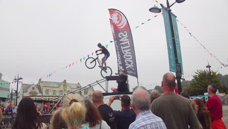 El-Hombre-Realiza-Un-Truco-Peligroso-En-Una-Bicicleta-De-Montaña-En-Truro,-Cornwall,-Inglaterra-Con-La-Audiencia-Mirando