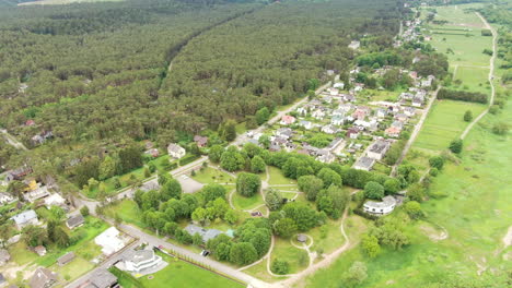 Small-Lithuanian-town-with-forest-and-river-on-sides,-aerial-view