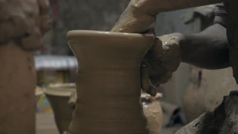 Close-up-view-of-clay-vessel-being-shaped-by-potter-hands,-rotating-on-the-potters-wheel