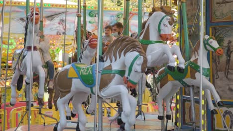 masked-dads-and-kids-riding-on-carousel-at-amusement-park-during-Covid19-pandemic