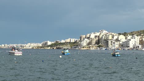 The-cityscape-of-Bugibba-city-in-Malta-with-houses,-seaview,-port,-small-boats-and-yachts