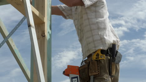 TILT-UP-House-Framing-Carpenter-On-A-Ladder-Hammering-Nails-Into-Wooden-Frame