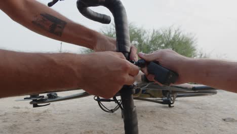 Nahaufnahme-Von-Zwei-Professionellen-Radfahrern,-Die-Ihre-Fahrräder-Reparieren-Und-Eine-Go-Pro-Kamera-Installieren,-Um-Sie-Auf-Die-Fahrt-In-Der-Wüste-Vorzubereiten