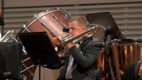 Focus-on-a-young-man-playing-the-trombone-with-an-orchestra,-Liepāja-Symphony-Orchestra-season-opening-concert,-concert-hall-Great-Amber-,-medium-distant-shot